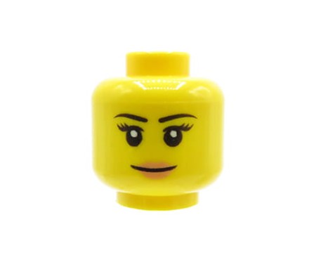 Głowa figurki LEGO w kolorze żółtym, damska, z uśmiechniętą miną, czarnymi cienkimi brwiami, rzęsami i ustami w kolorze brzoskwiniowym.