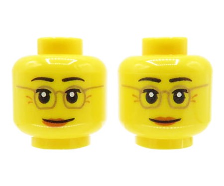 Głowa figurki LEGO w kolorze żółtym, dwustronna, damska, okulary, ciemne brwi, kurze łapki, ciemno pomarańczowe usta, uniesione brwi, delikatny uśmiech / neutralna mina.